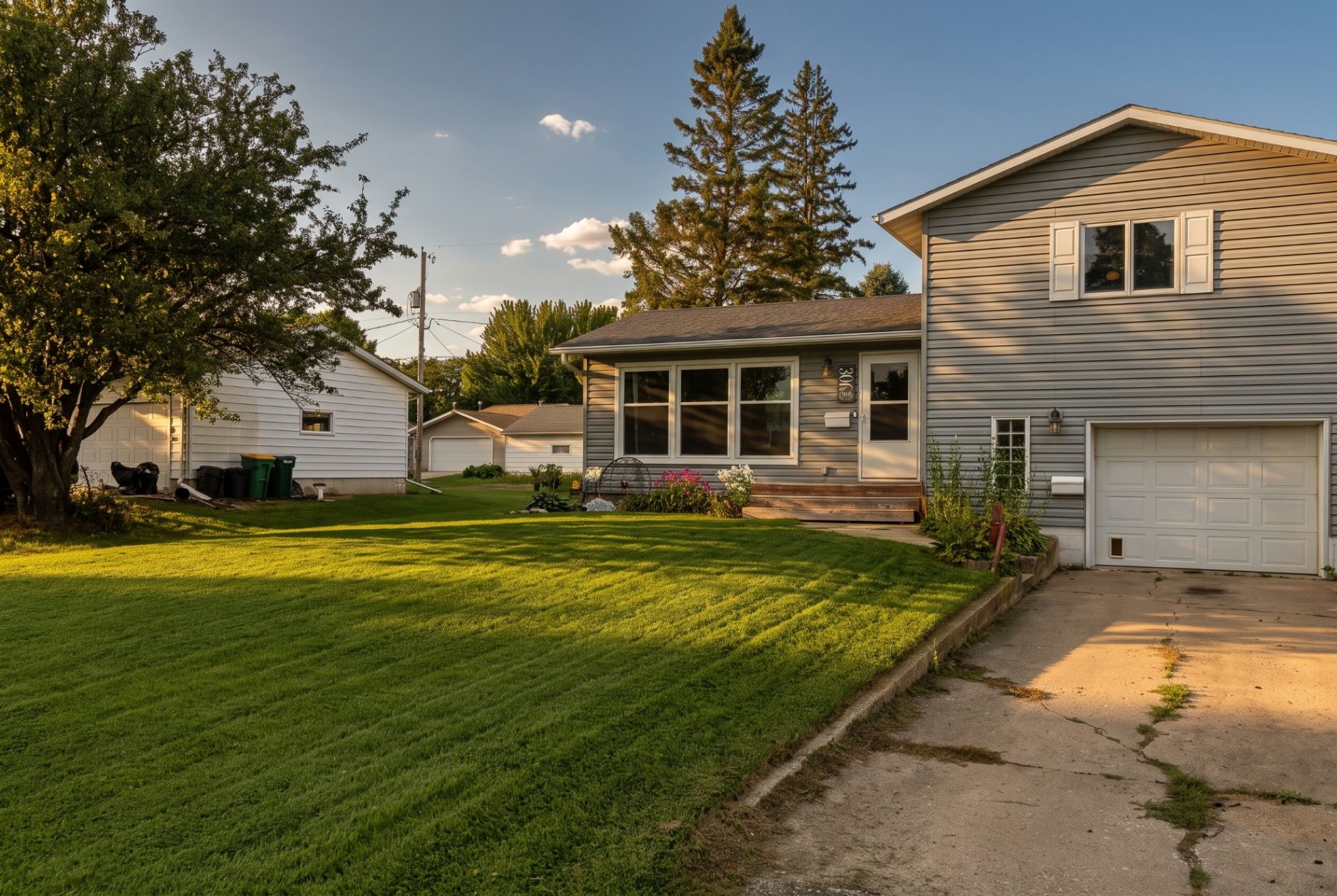 Welcoming Clear Lake home with mature trees, a spacious lawn, and warm evening light