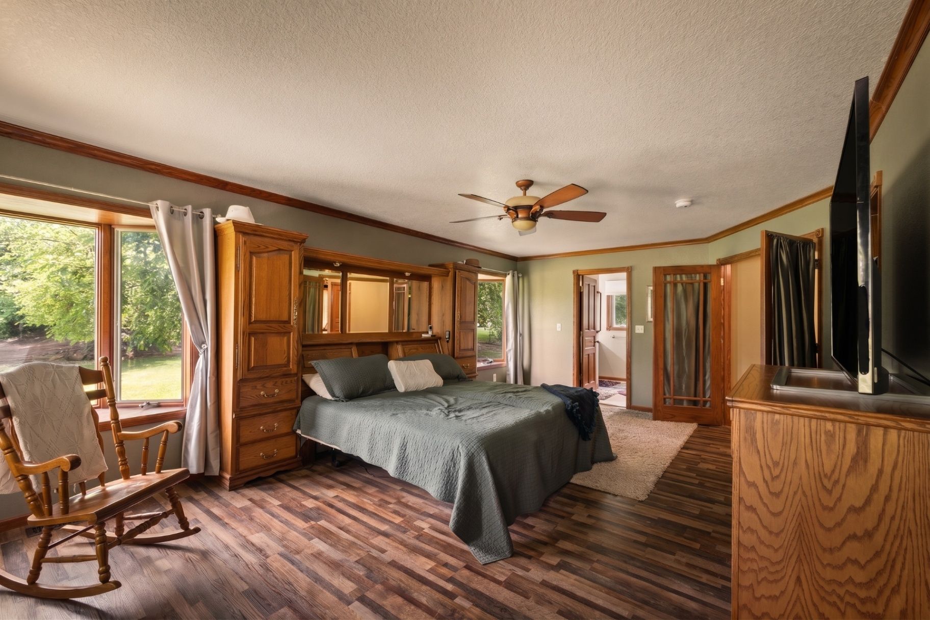 Bright primary bedroom with natural light and warm wood details